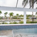 Screened pool area overlooking a canal at a luxury home renovation project in Miromar Lakes, Florida