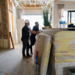 Project team reviewing interior renovation progress beside stacked drywall in a Miromar Lakes luxury home